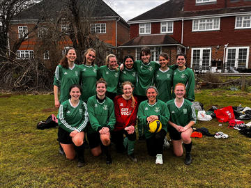 Holly (second from right, front row) poses with her college football team. 11 women wearing green jerseys stand/kneel in two rows, with a woman in red jersey in the centre front. 